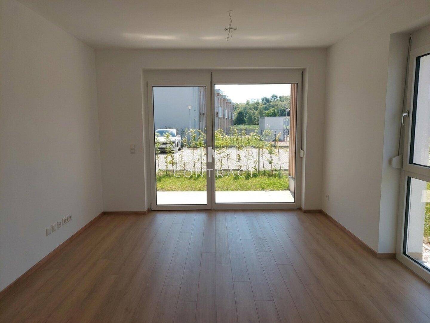 Heller Wohnraum mit Laminatboden und großer Schiebetür, die Zugang zum Gartenbereich bietet.