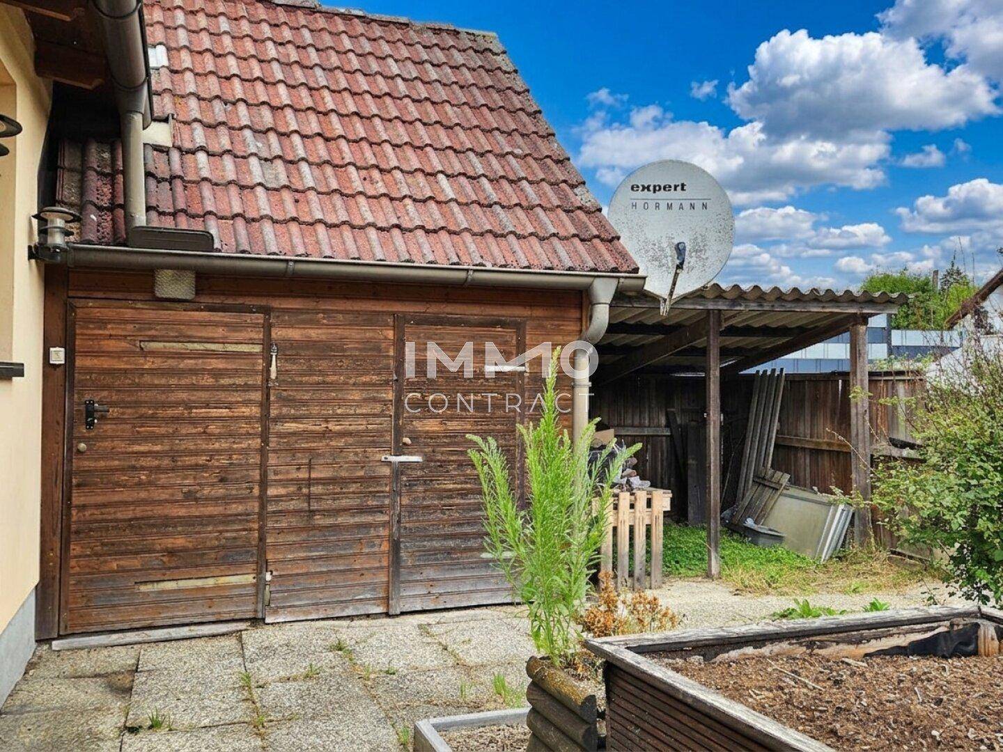 Hölzerne Garage oder Schuppen mit Satteldach und Satellitenschüssel.