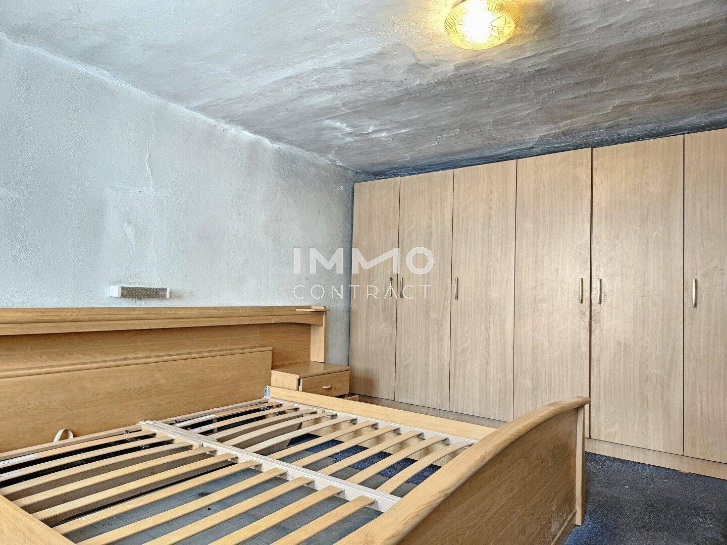Schlafzimmer mit Holzbett und eingebauten Kleiderschränken entlang der Wand.
