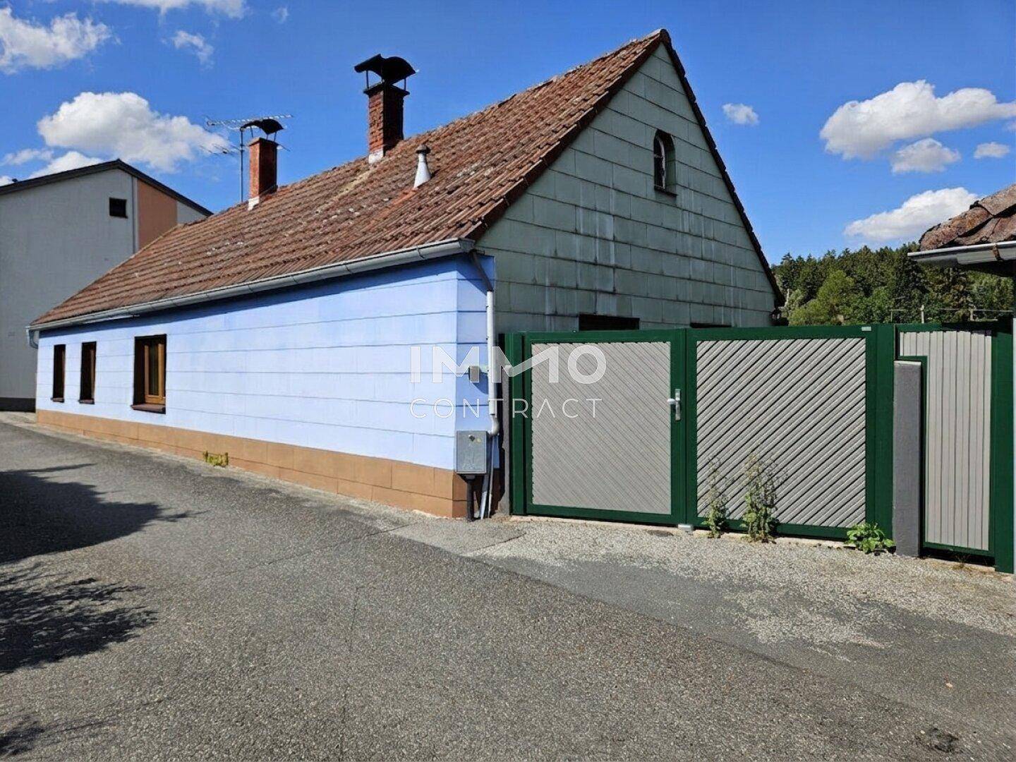 Seitenansicht eines älteren Hauses mit blauer Fassade und Satteldach.
