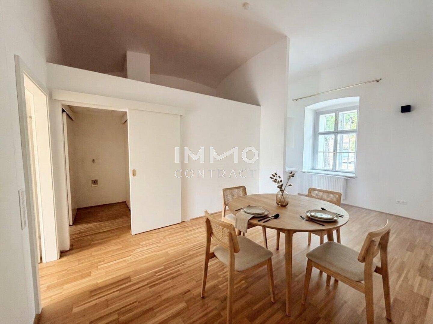 Essbereich mit modernem Holztisch und Stühlen, Parkettboden und viel Tageslicht durch das Fenster.