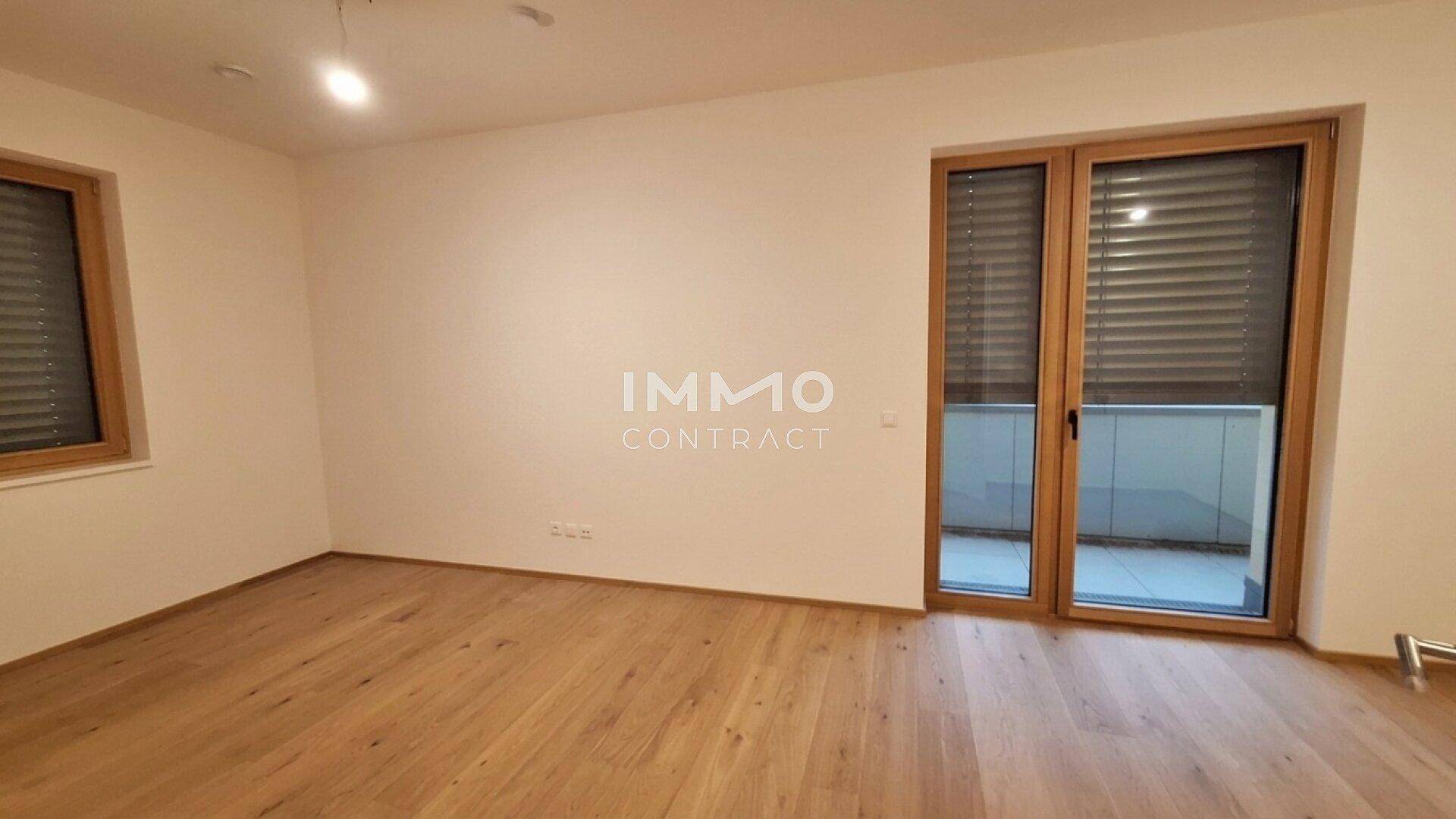 Helles Zimmer mit Holzboden und Zugang zu einem Balkon, ideal als Wohn- oder Schlafbereich.