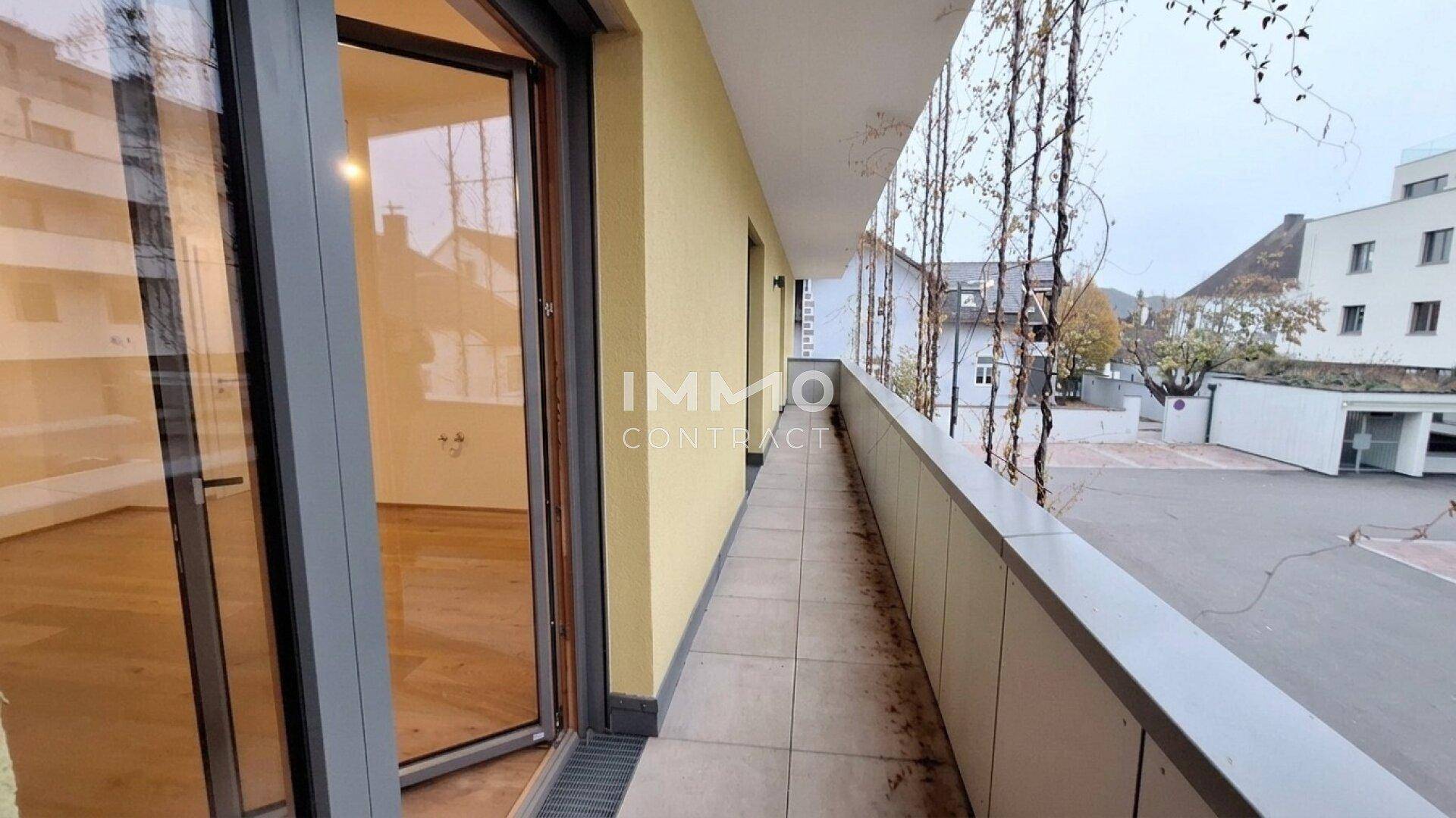 Langer Balkon mit Blick auf die Umgebung und Zugang zu einem hellen Innenraum.