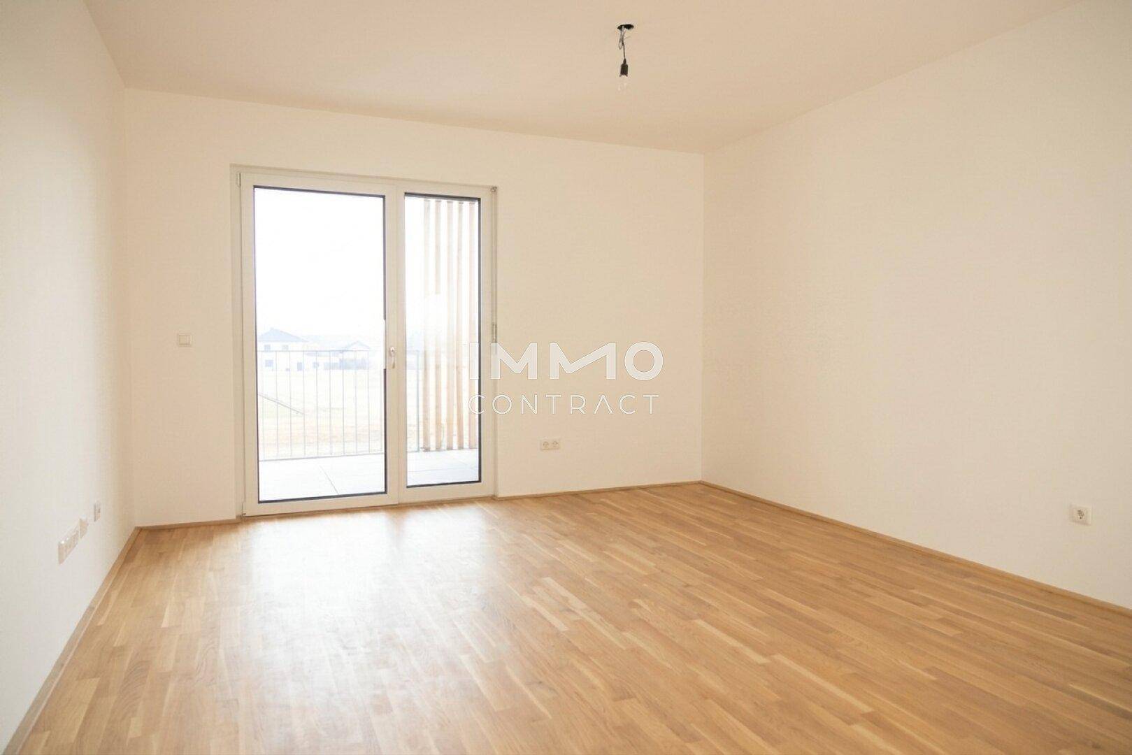 Leeres Schlafzimmer mit Holzboden und Zugang zu einem Balkon mit weitem Ausblick.
