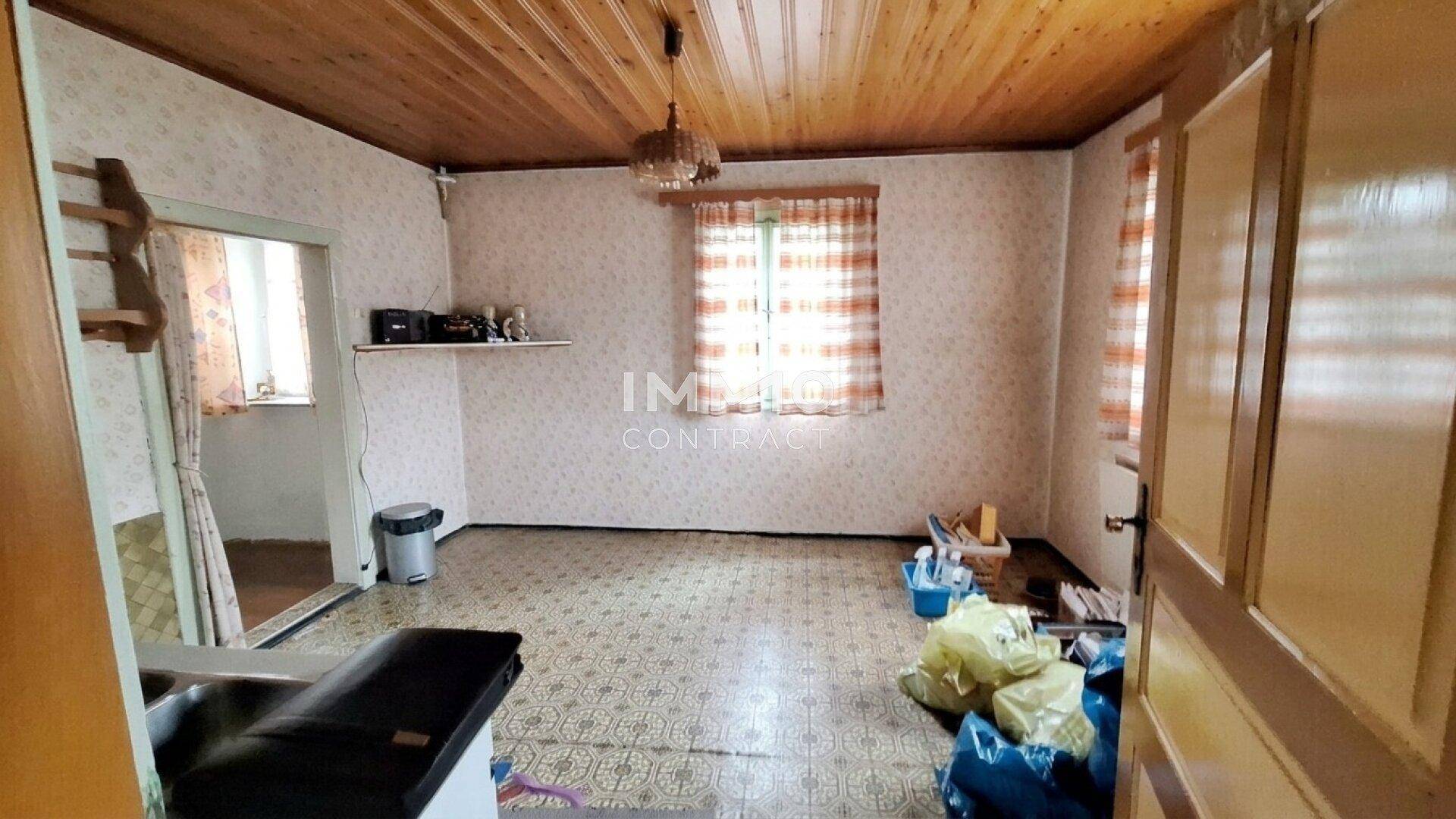 Alterer Raum mit gemusterten Tapeten, Holzdecke und einem Fenster, der auf Renovierung wartet.
