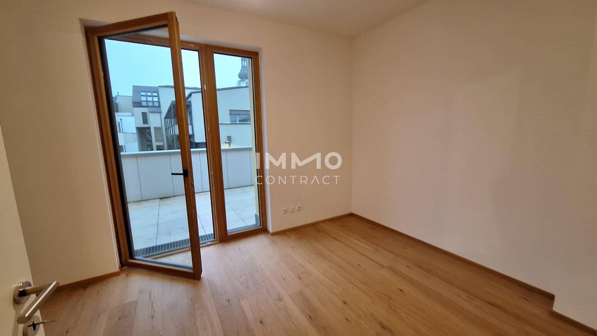 Schlafzimmer mit Holzboden und direktem Zugang zu einer sonnigen Terrasse.