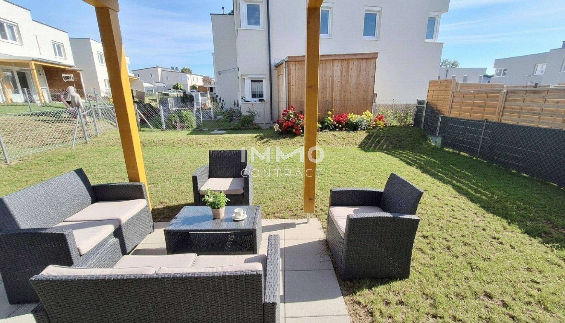 Gepflegter Gartenbereich mit Rasenfläche, überdachtem Sitzbereich und Blick auf die Nachbarschaft.