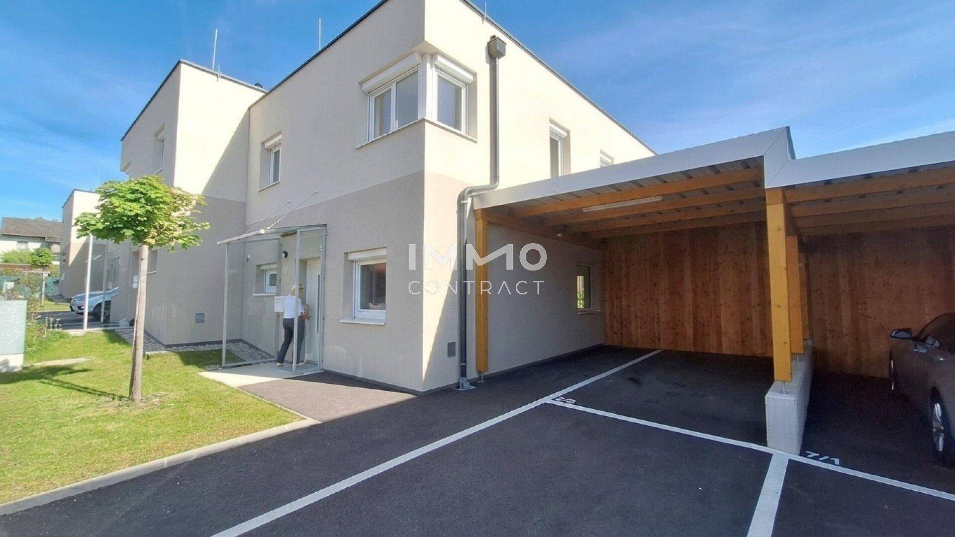 Vorderansicht eines modernen Neubaus mit Carport und gepflegter Zufahrt, bietet praktischen Parkraum.