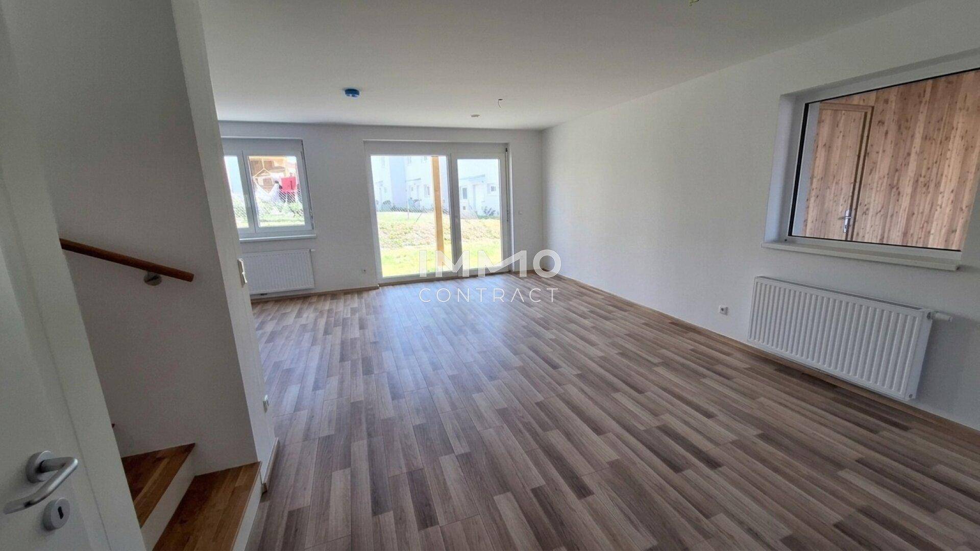 Heller Wohnbereich mit modernem Laminatboden und Zugang zum Garten, bietet viel natürliches Licht.