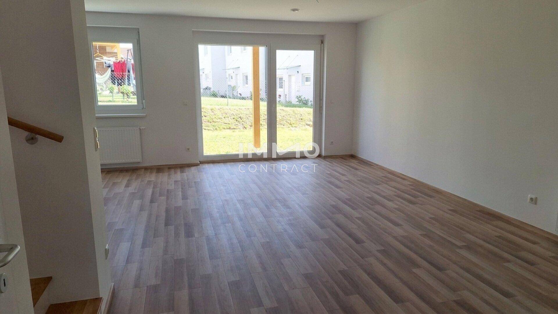 Lichtdurchfluteter Wohnraum mit Laminatboden und direktem Zugang zum Garten, bietet eine angenehme Atmosphäre.