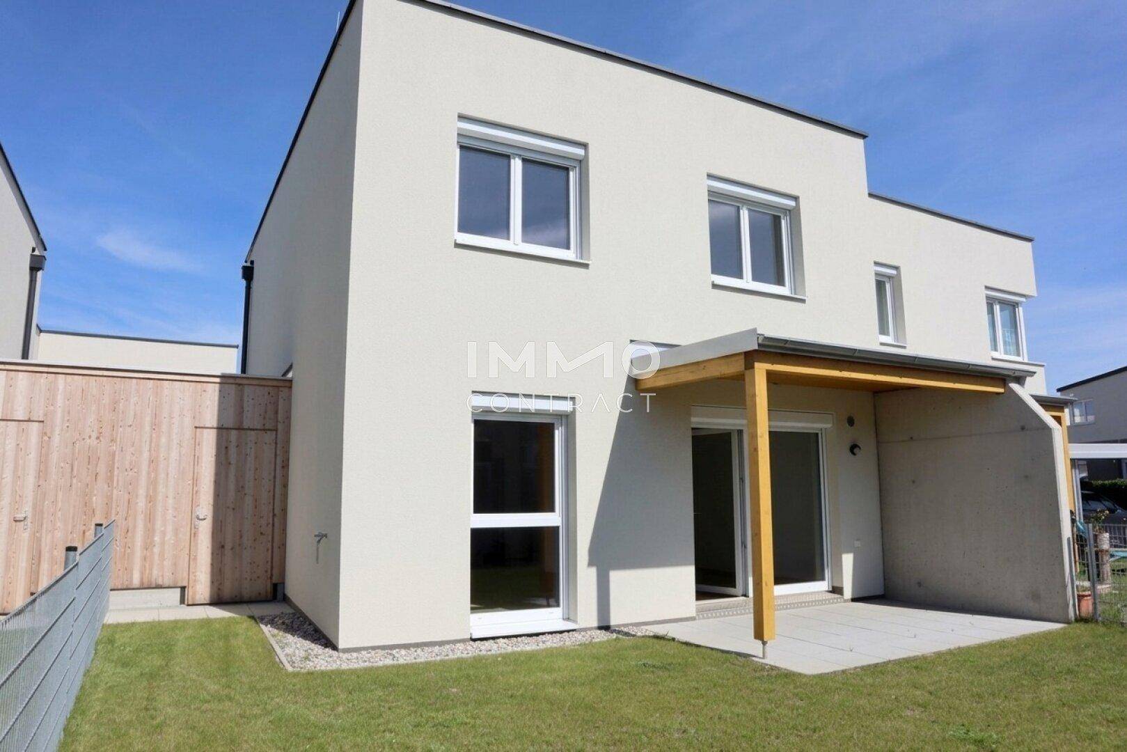 Rückseite eines Reihenhauses mit privatem Garten, Rasenfläche und überdachter Terrasse.