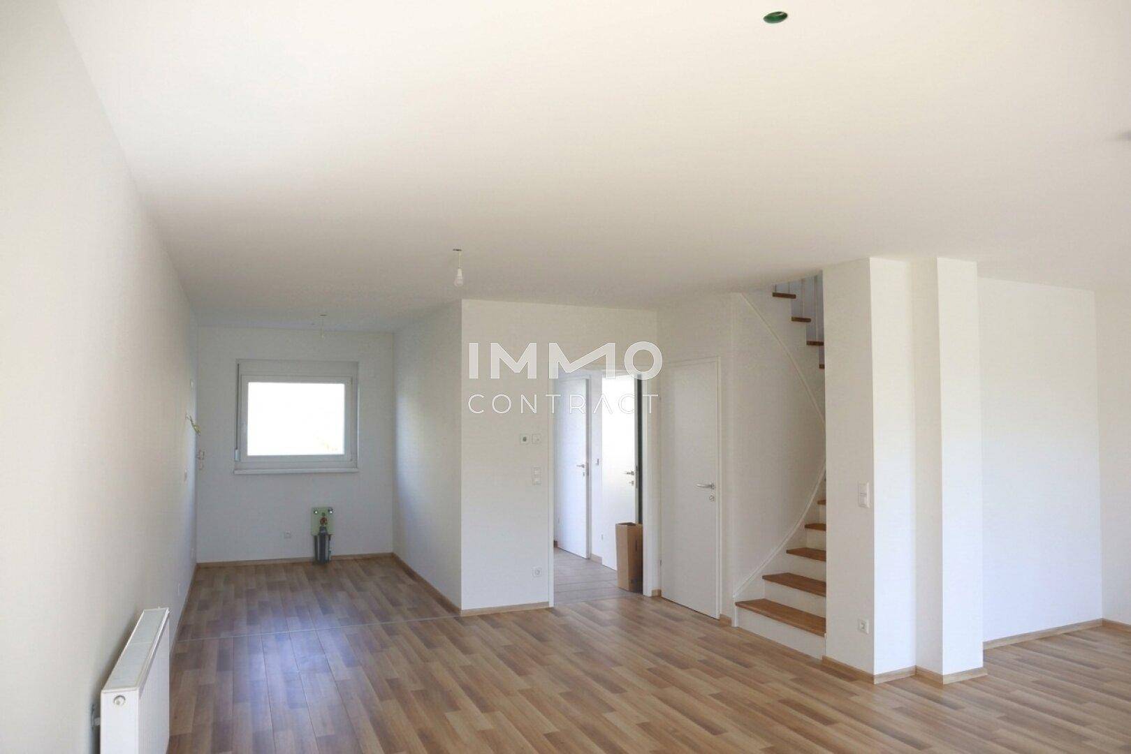 Geräumiges Wohnzimmer mit Laminatboden und Treppe zum Obergeschoss, bereit für die Einrichtung.
