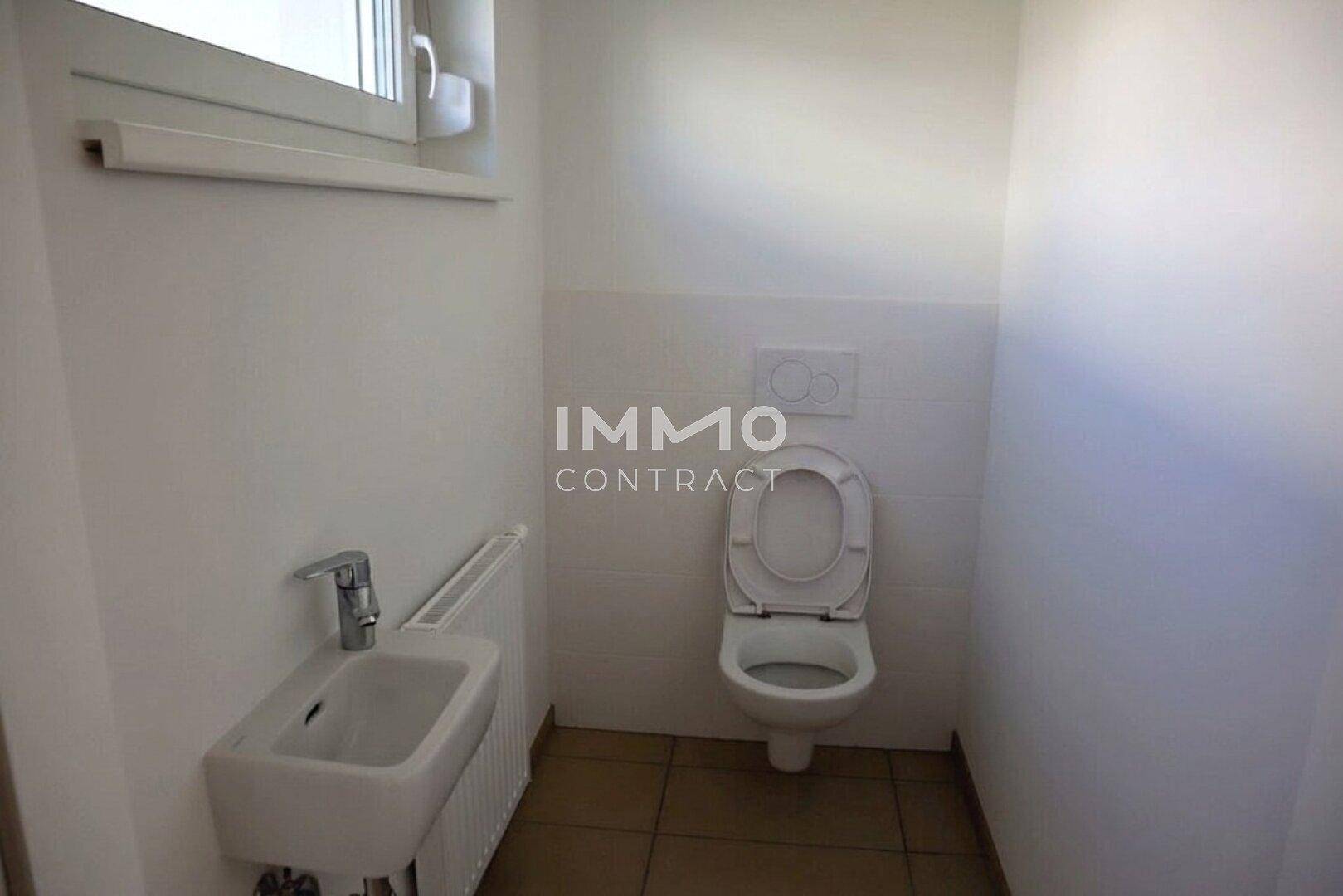 Separates Gäste-WC mit Fenster, Wand-WC und kleinem Handwaschbecken.