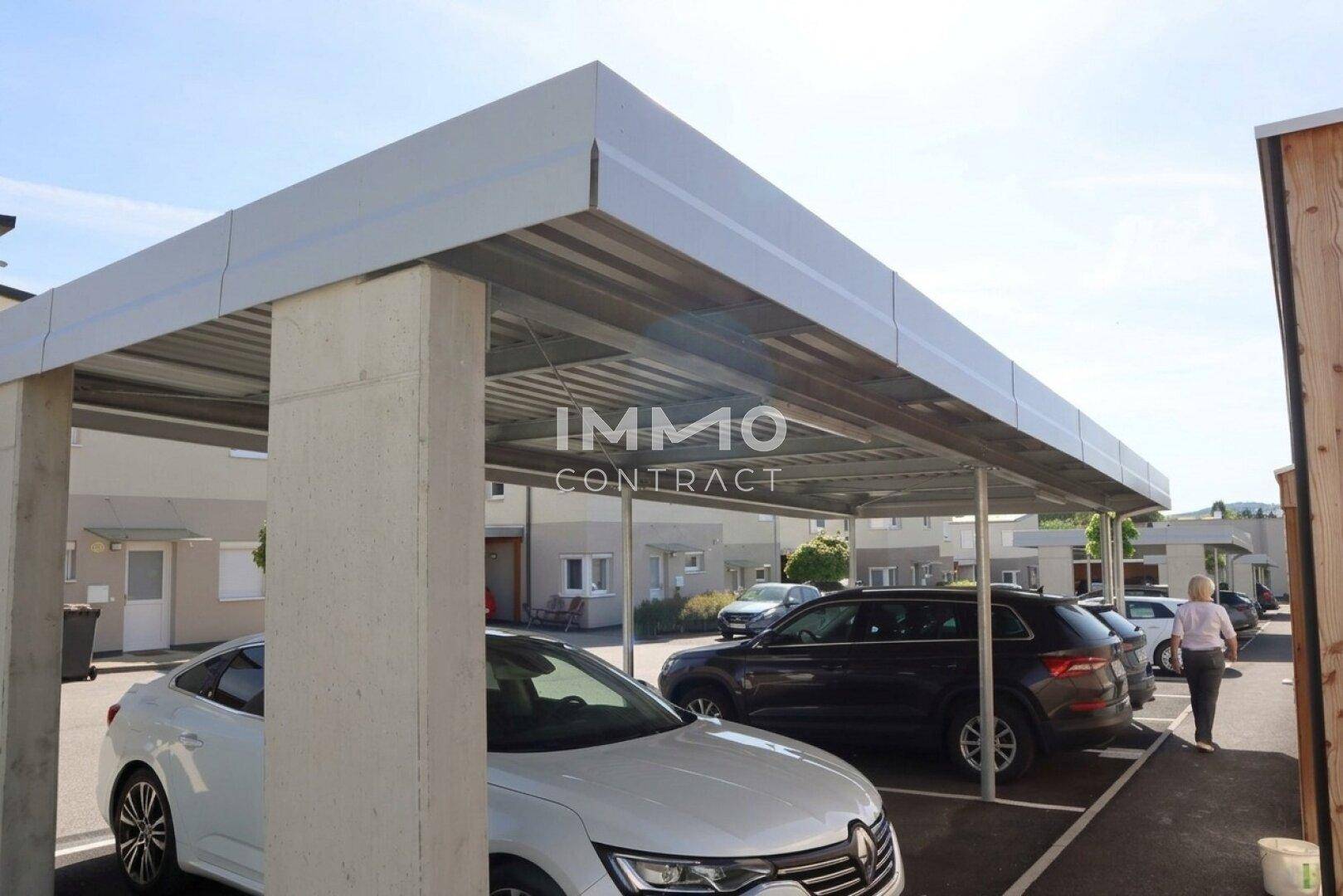 Überdachte Parkplätze in einem Carport-Bereich für mehrere Fahrzeuge der Wohnanlage.