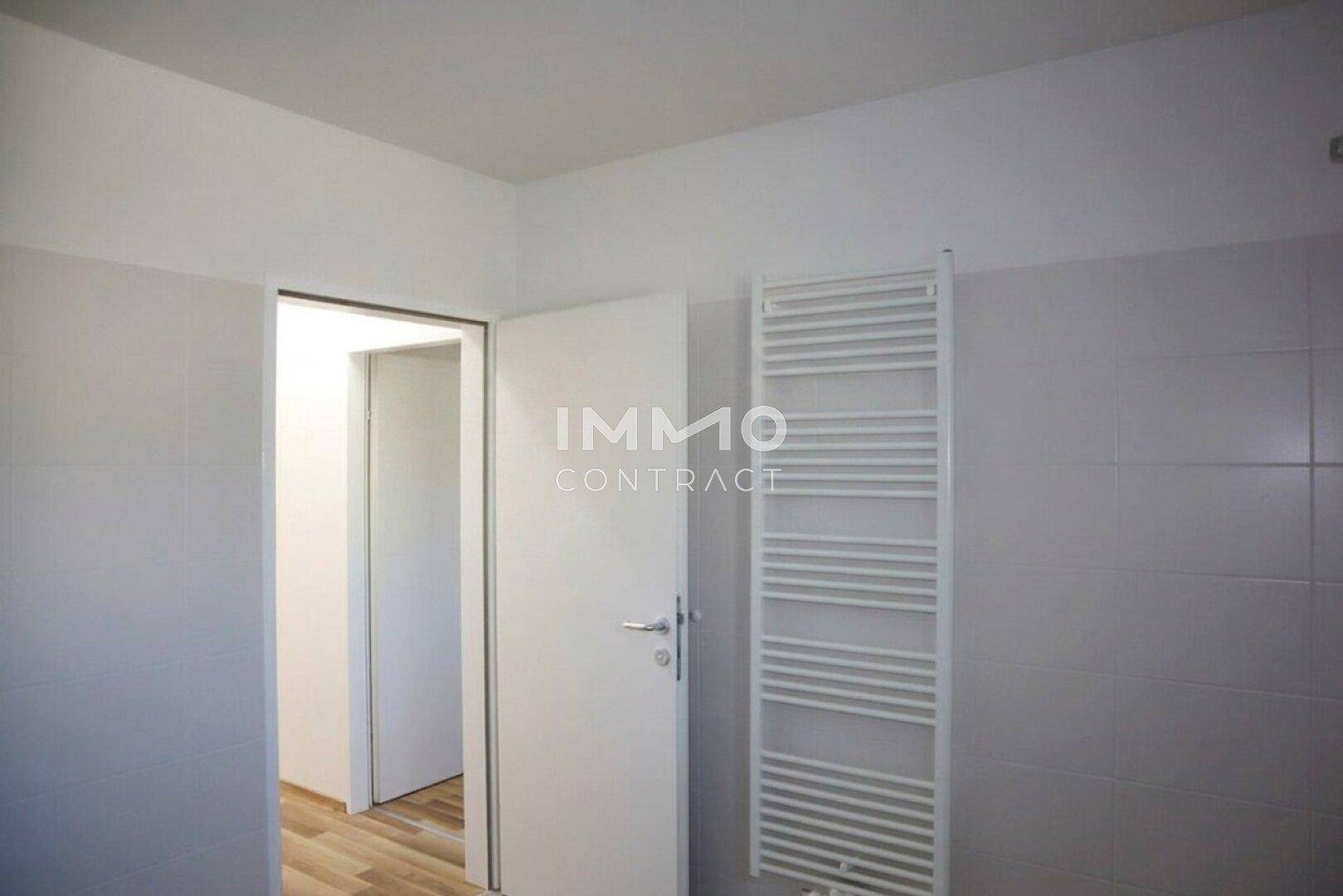 Funktionales Badezimmer mit weiß gefliesten Wänden und einem beheizten Handtuchhalter.