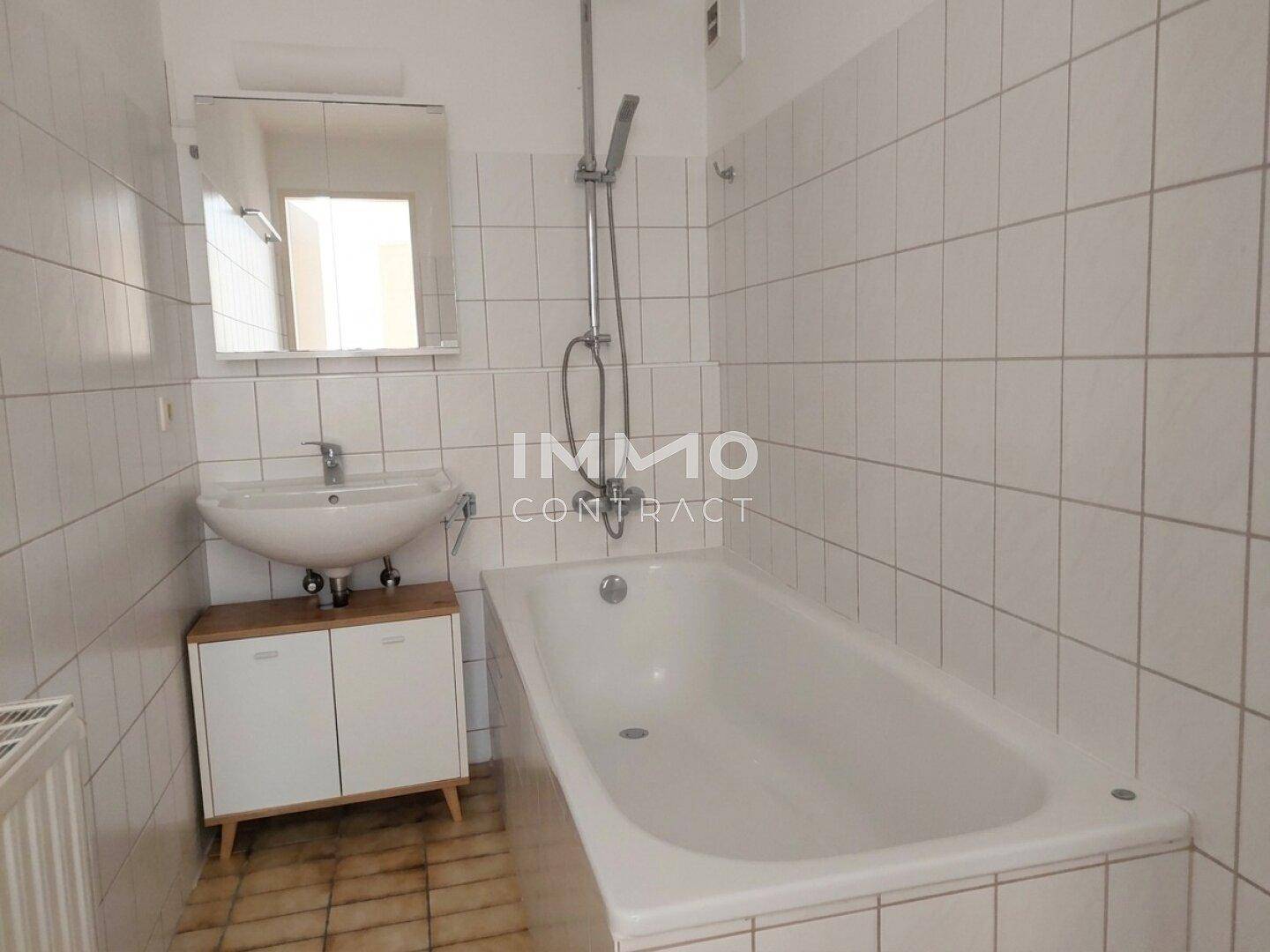 Gefliestes Badezimmer mit Badewanne, Waschbecken und Heizkörper, in gutem Zustand.