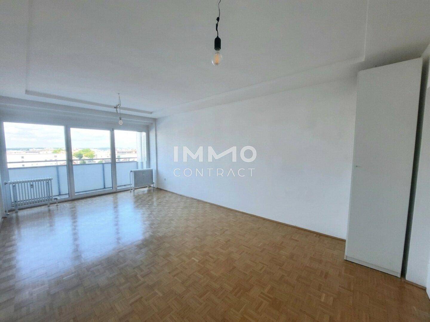 Geräumiges Wohnzimmer mit Parkettboden, großen Fenstern und einem praktischen Einbauschrank.