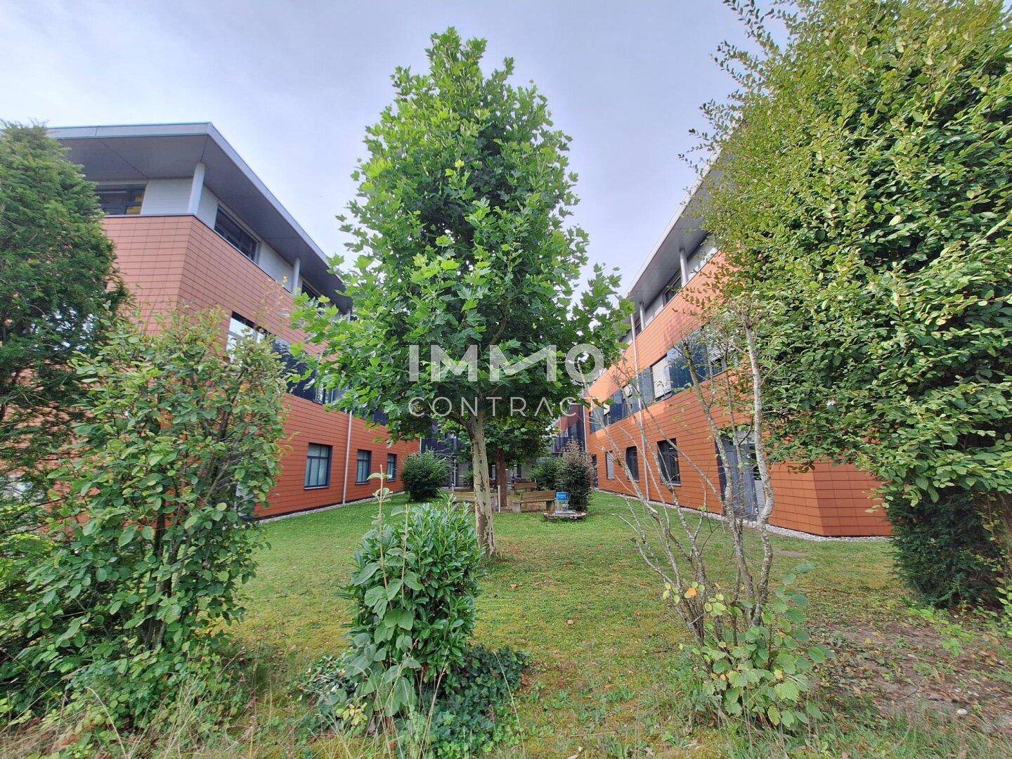 Grünfläche mit Bäumen zwischen den Gebäudeteilen des modernen Bürokomplexes.