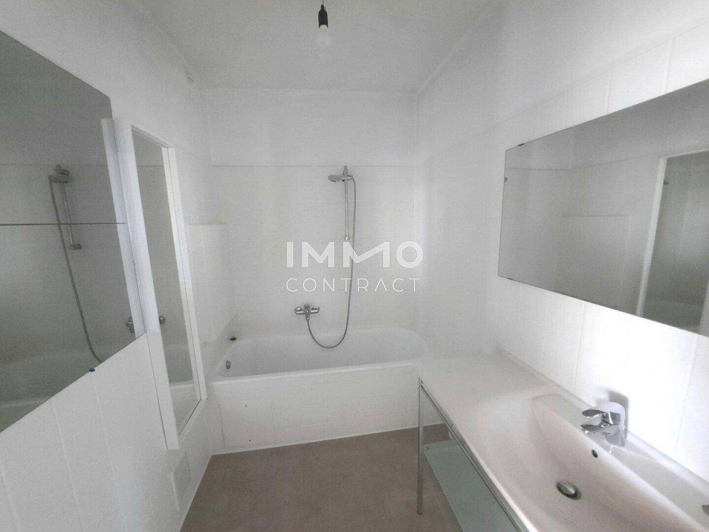 Funktionales Badezimmer mit Badewanne, Duschvorrichtung, Waschbecken und großen Spiegeln.