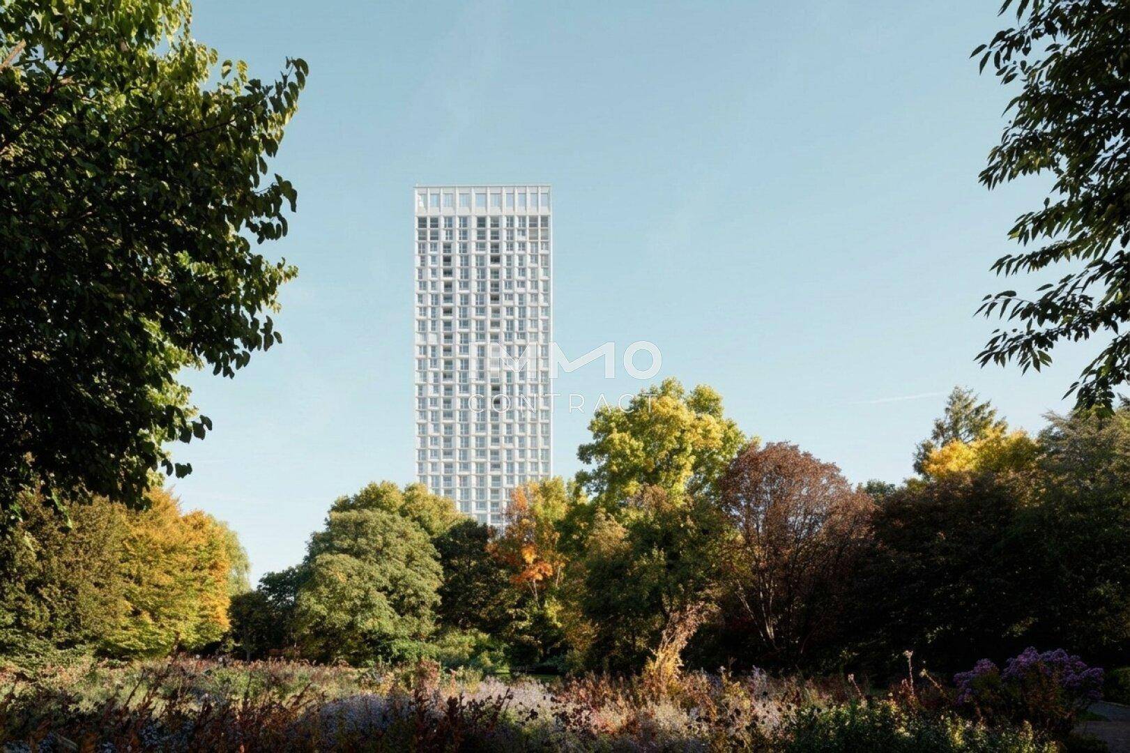 Hohes modernes Gebäude inmitten einer grünen Landschaft mit Herbstbäumen.