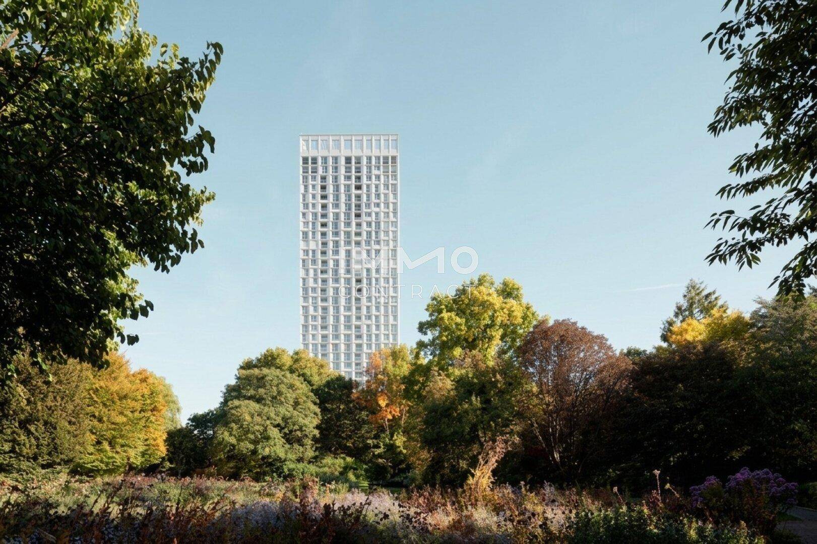 Zeitgenössisches Hochhaus inmitten von Bäumen und Grünflächen mit klarem Himmel.