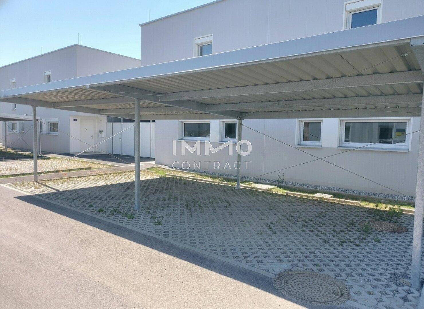 Überdachter Carport-Bereich mit mehreren Stellplätzen vor der modernen Wohnanlage.
