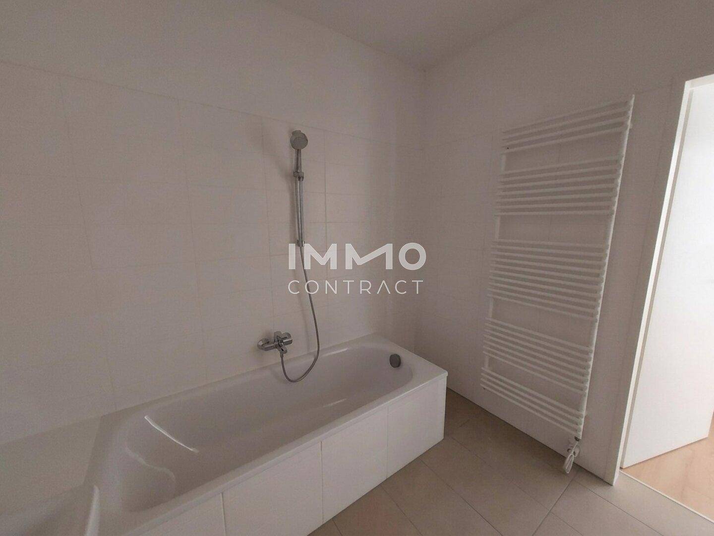 Helles Badezimmer mit Badewanne und einem praktischen beheizten Handtuchhalter.