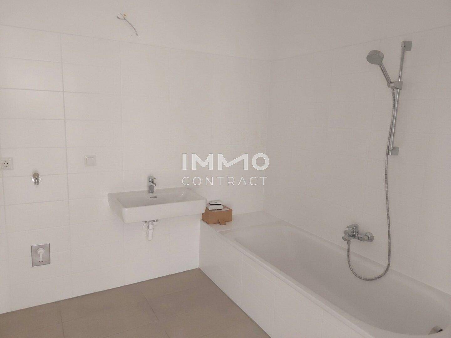 Helles Badezimmer mit Badewanne, Wandwaschbecken und weißen Fliesen.