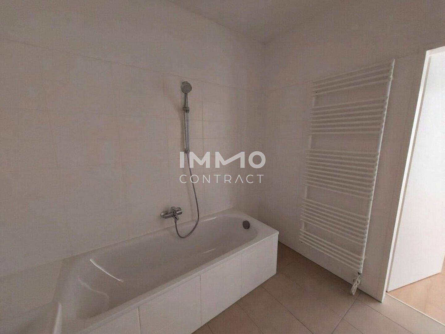 Modernes Badezimmer mit weiß gefliesten Wänden, Badewanne und beheiztem Handtuchhalter.