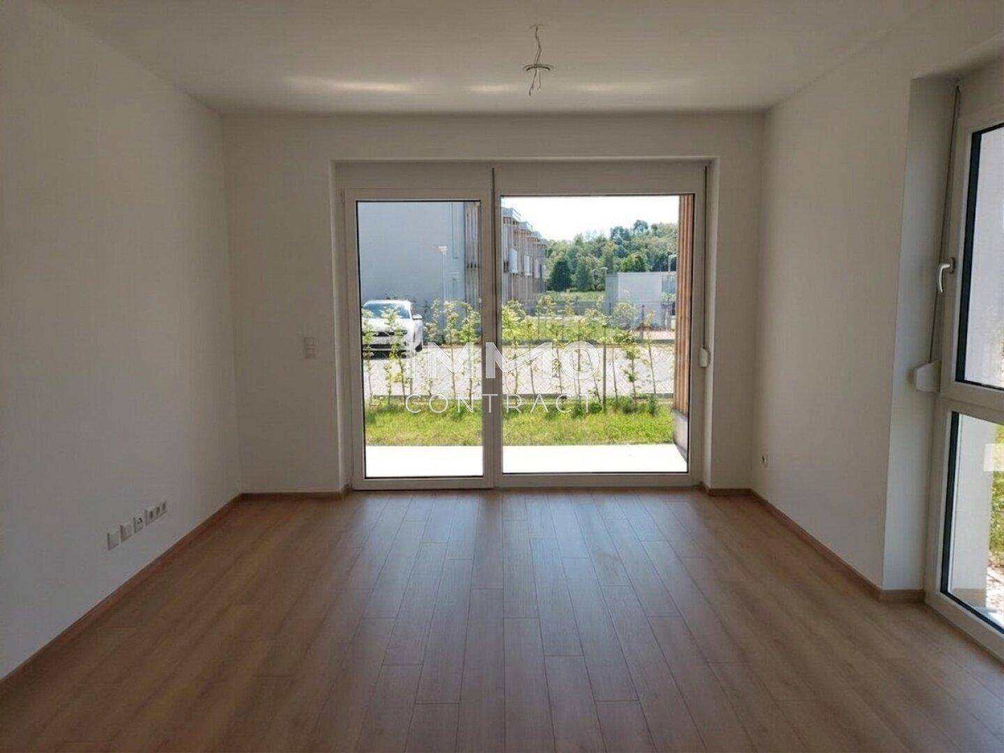 Heller Wohnraum mit Laminatboden und großem Schiebetürzugang zum Gartenbereich.