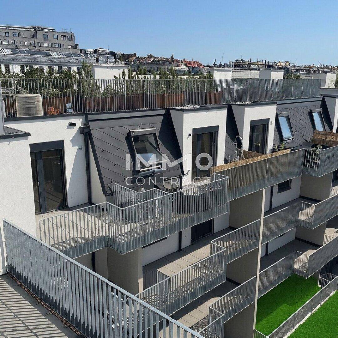 Moderne Gebäudefassade mit mehreren Balkonen und Dachterrassen unter strahlend blauem Himmel.