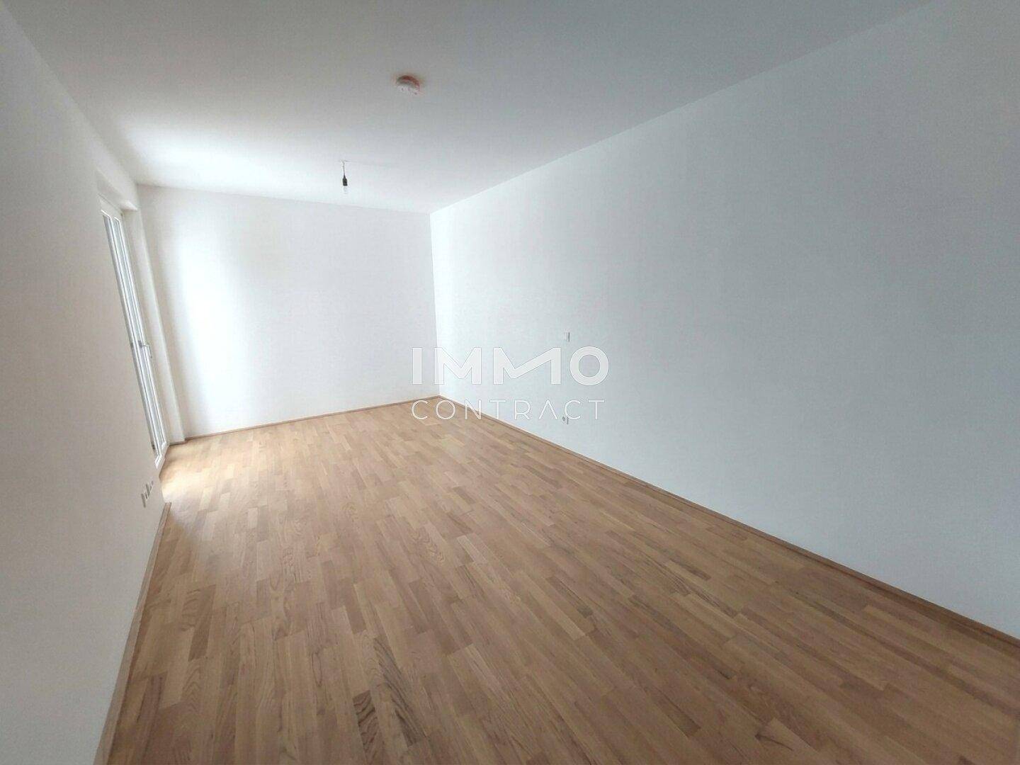 Heller, leerer Raum mit weißen Wänden und hochwertigem Holzparkettboden, bereit zum Einzug.