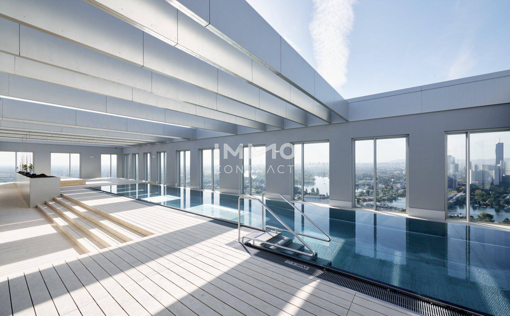 Moderner Innenpoolbereich mit großen Fenstern und Panoramablick auf die Stadt und das Wasser.