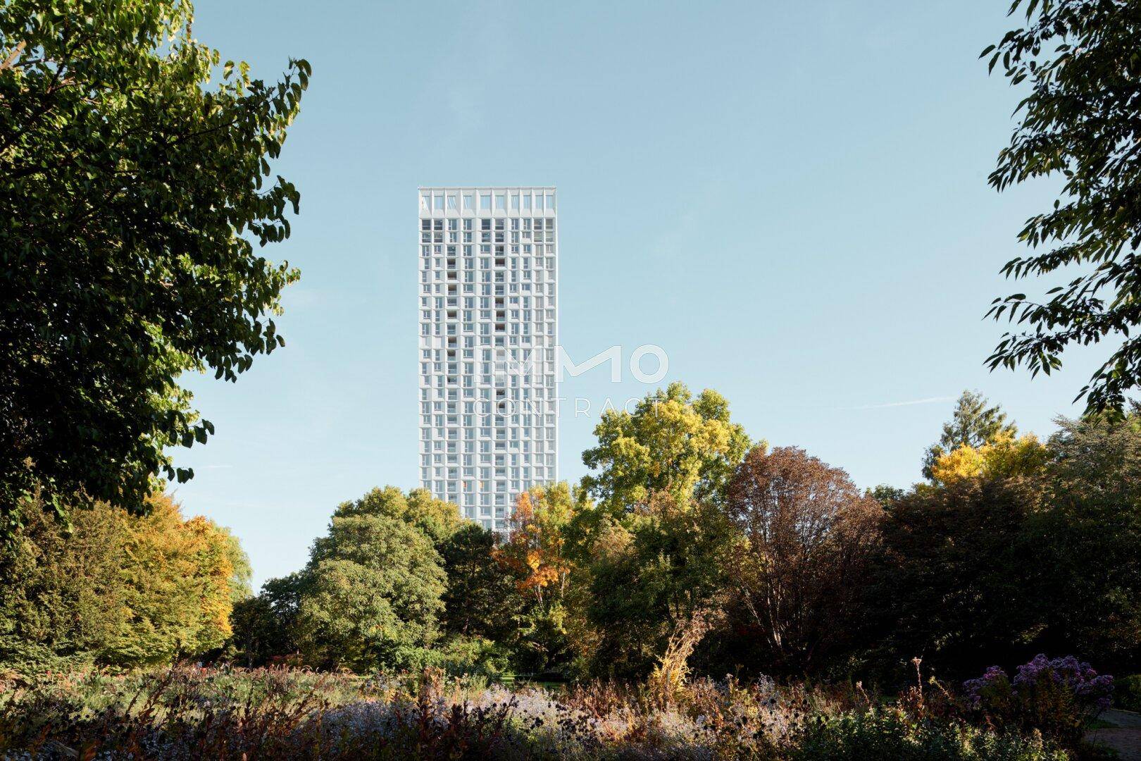 Zeitgenössisches Hochhaus mit markanter Architektur, eingebettet in eine grüne Parklandschaft.