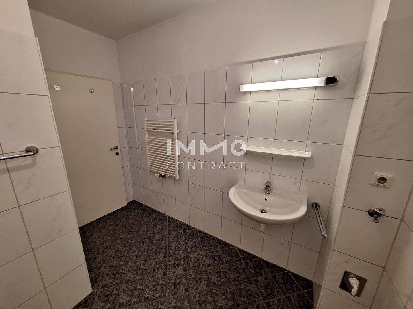 Gefliestes Badezimmer mit Waschbecken und beheiztem Handtuchhalter, ohne Dusche oder Badewanne.