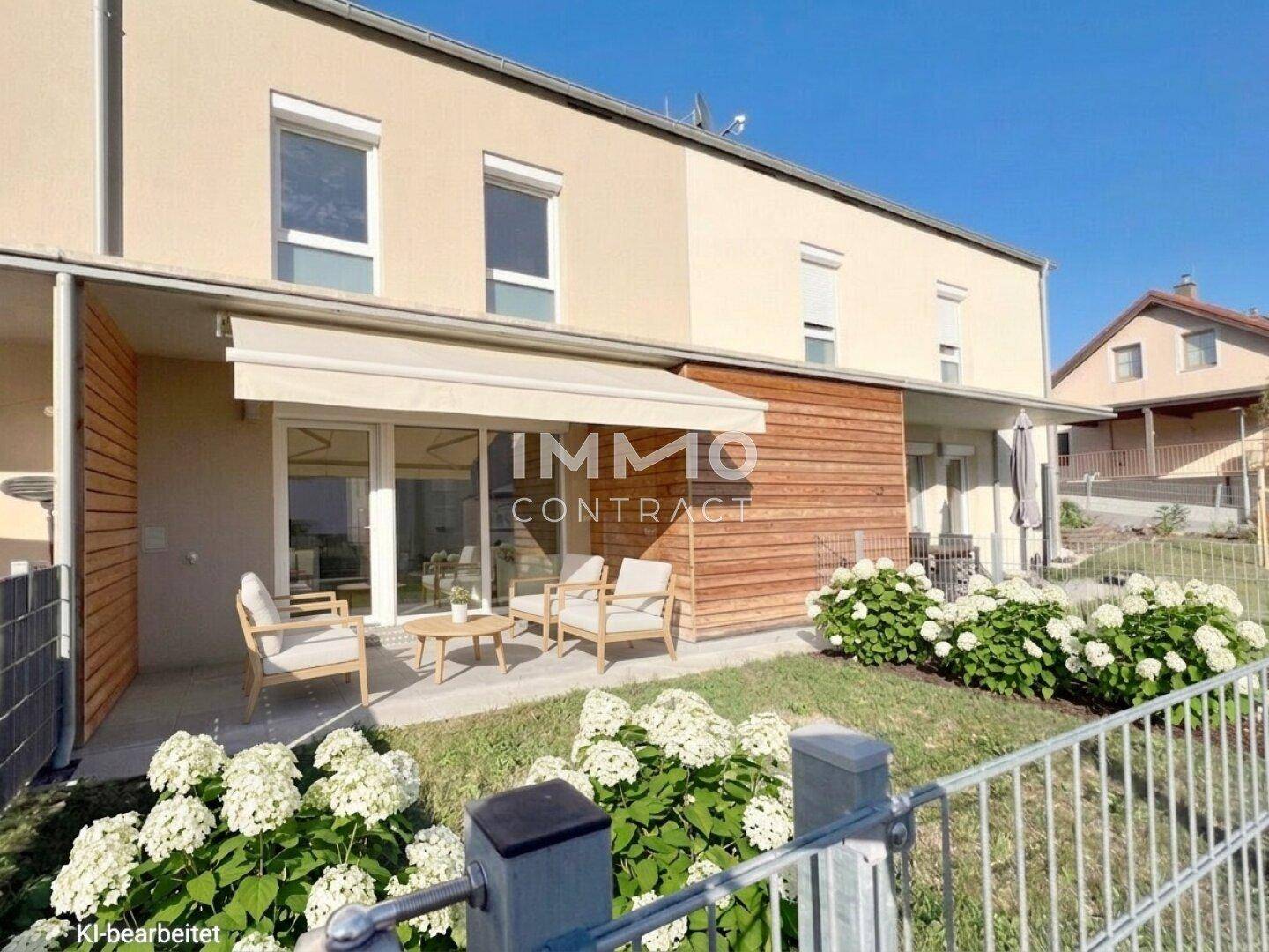 Gemütliche Terrasse mit Gartenmöbeln und Markise, umgeben von blühenden Hortensien und Rasenfläche.