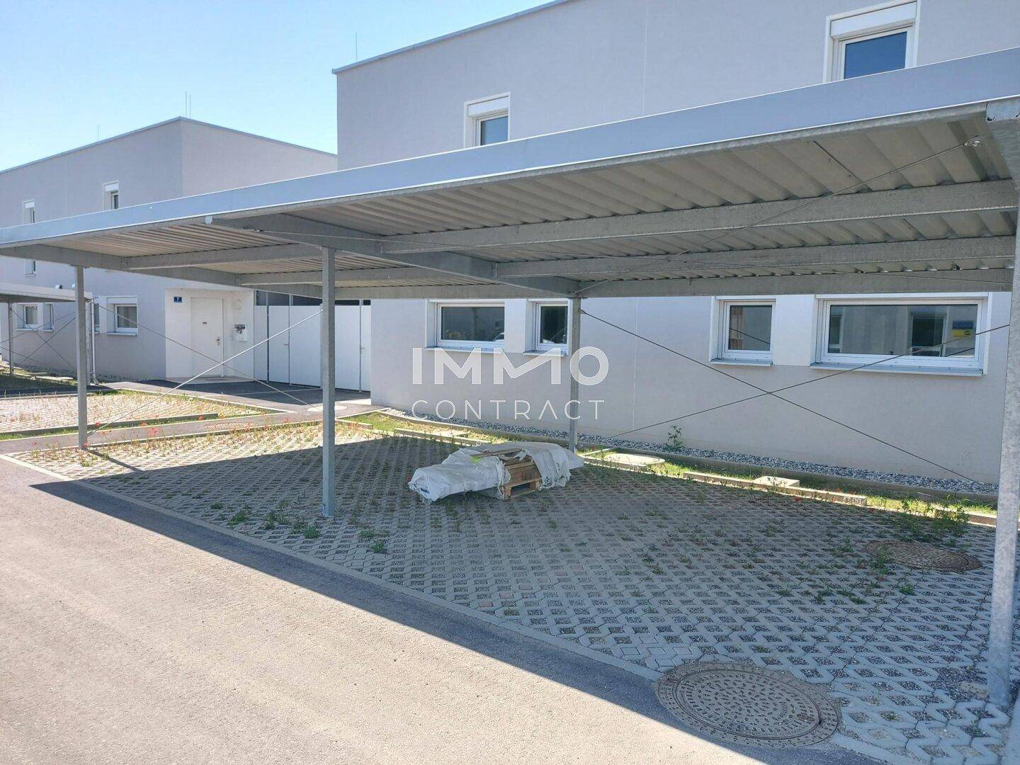 Überdachter Carport-Bereich vor dem modernen Reihenhaus mit Stellplätzen.