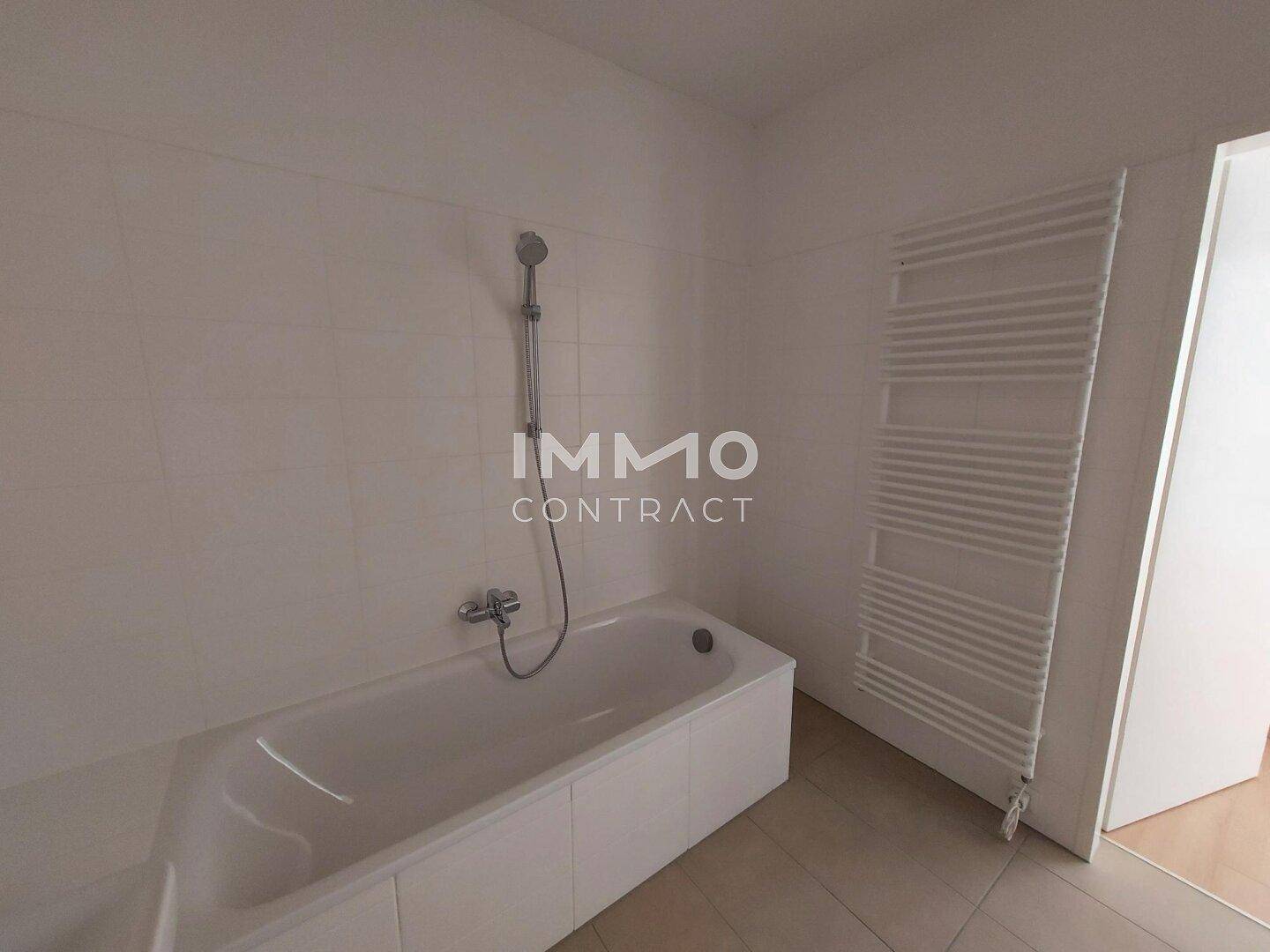 Helles Badezimmer mit eingebauter Badewanne und praktischem Handtuchheizkörper.