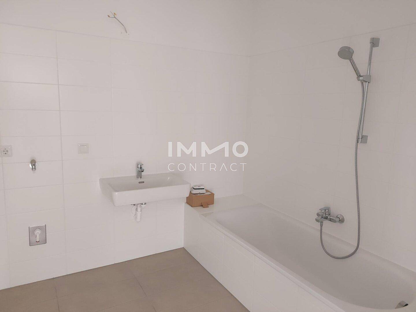 Modernes Badezimmer mit Badewanne, Waschbecken und Duschvorrichtung an der Wand.