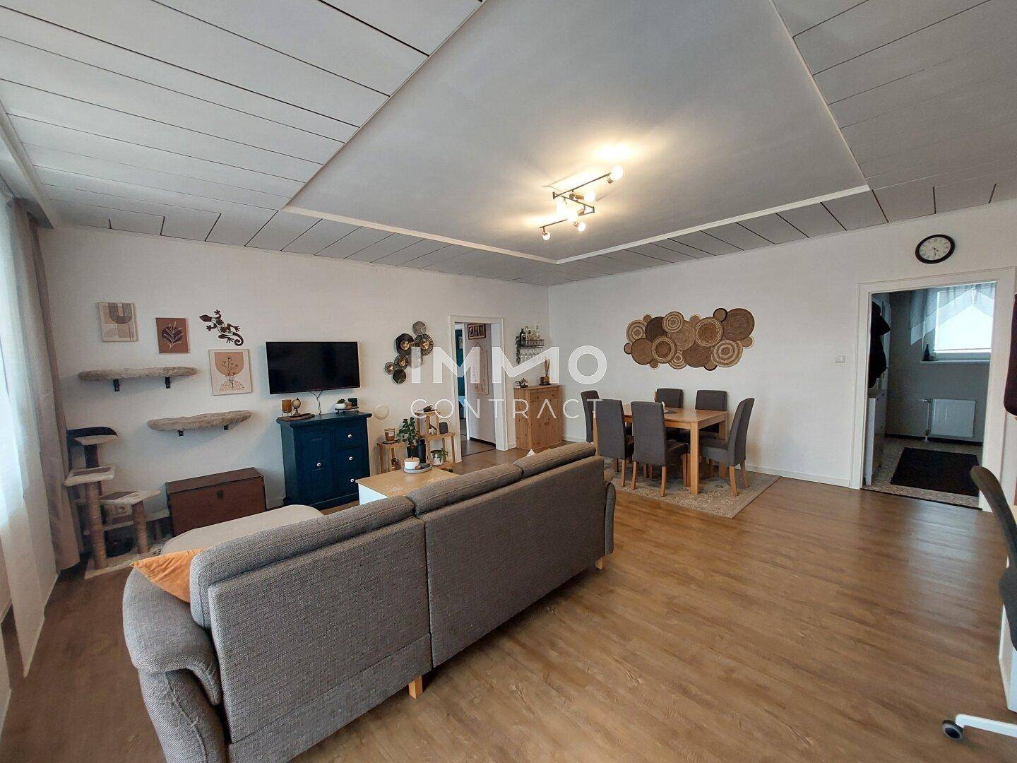 Geräumiger Wohn-Essbereich mit Sofa, Esstisch und hellem Laminatboden.