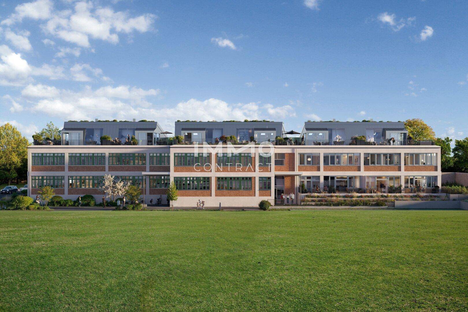 Moderne Gebäudefassade mit großen Fenstern, Dachterrassen und weitläufiger Grünfläche davor.