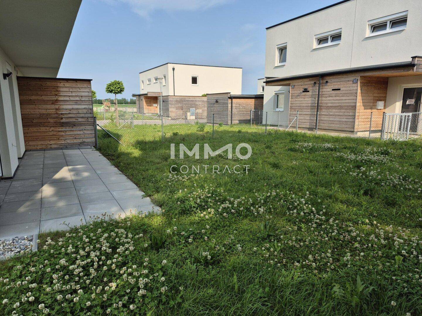 Gepflasterte Terrasse mit Blick auf den Garten und weitere moderne Reihenhäuser in der Umgebung.