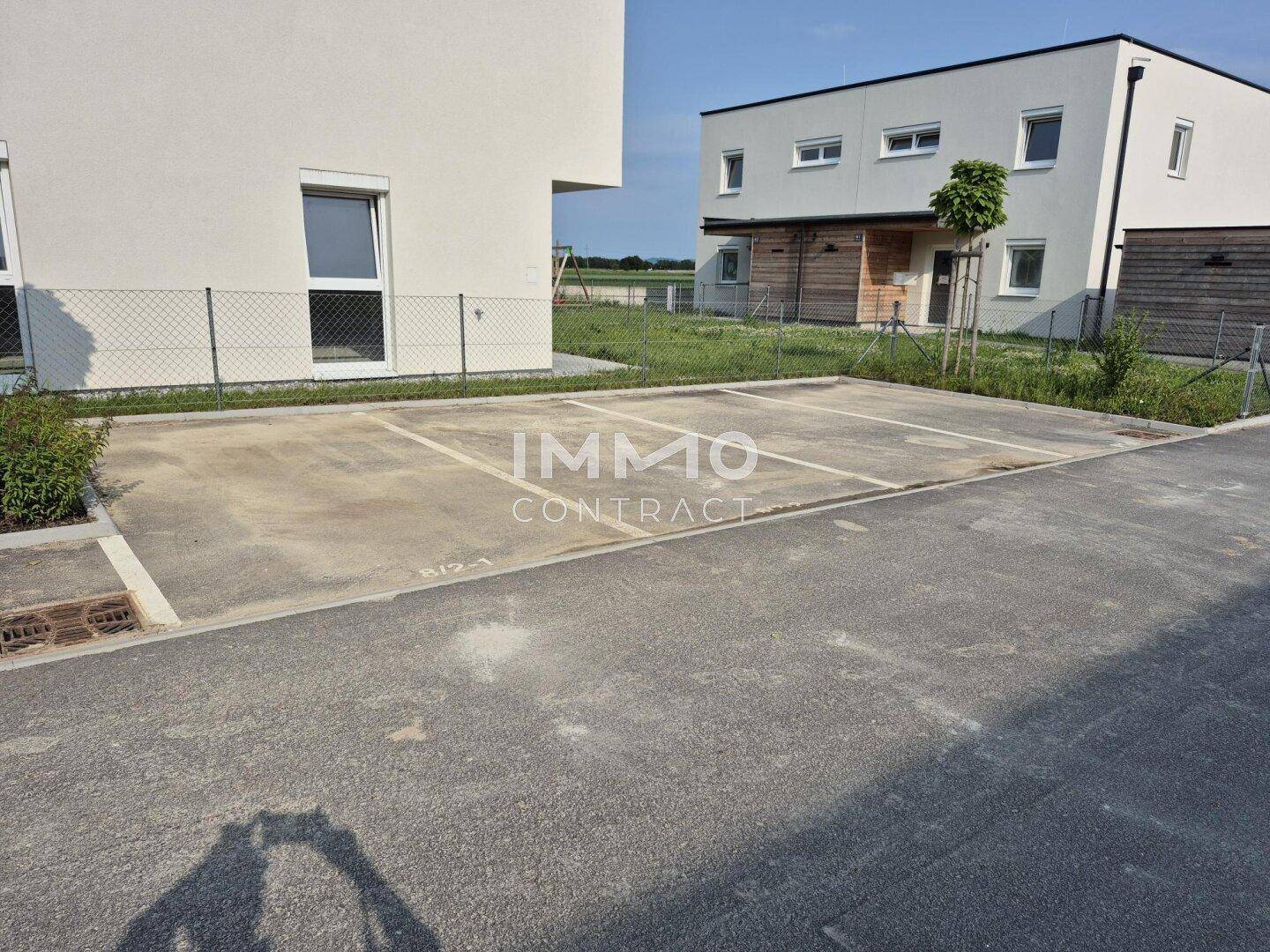Außenparkplätze mit Markierungen für mehrere Fahrzeuge vor den modernen Gebäuden.