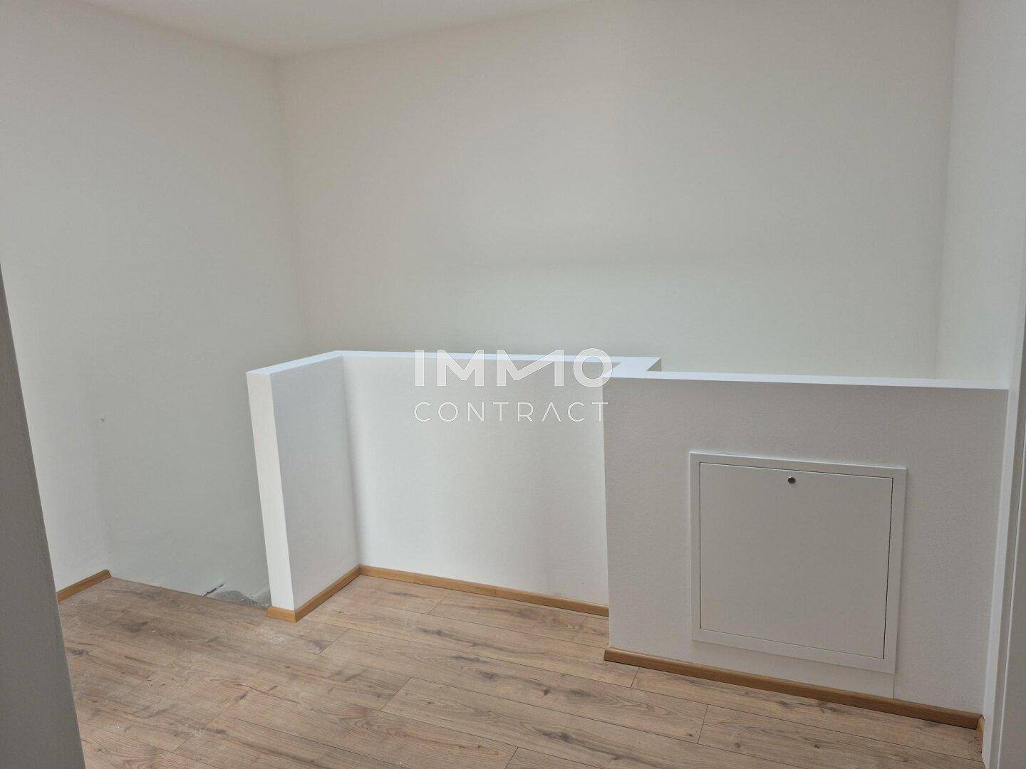 Heller Flurbereich im Obergeschoss mit Laminatboden und einer Zugangsklappe in der Wand.