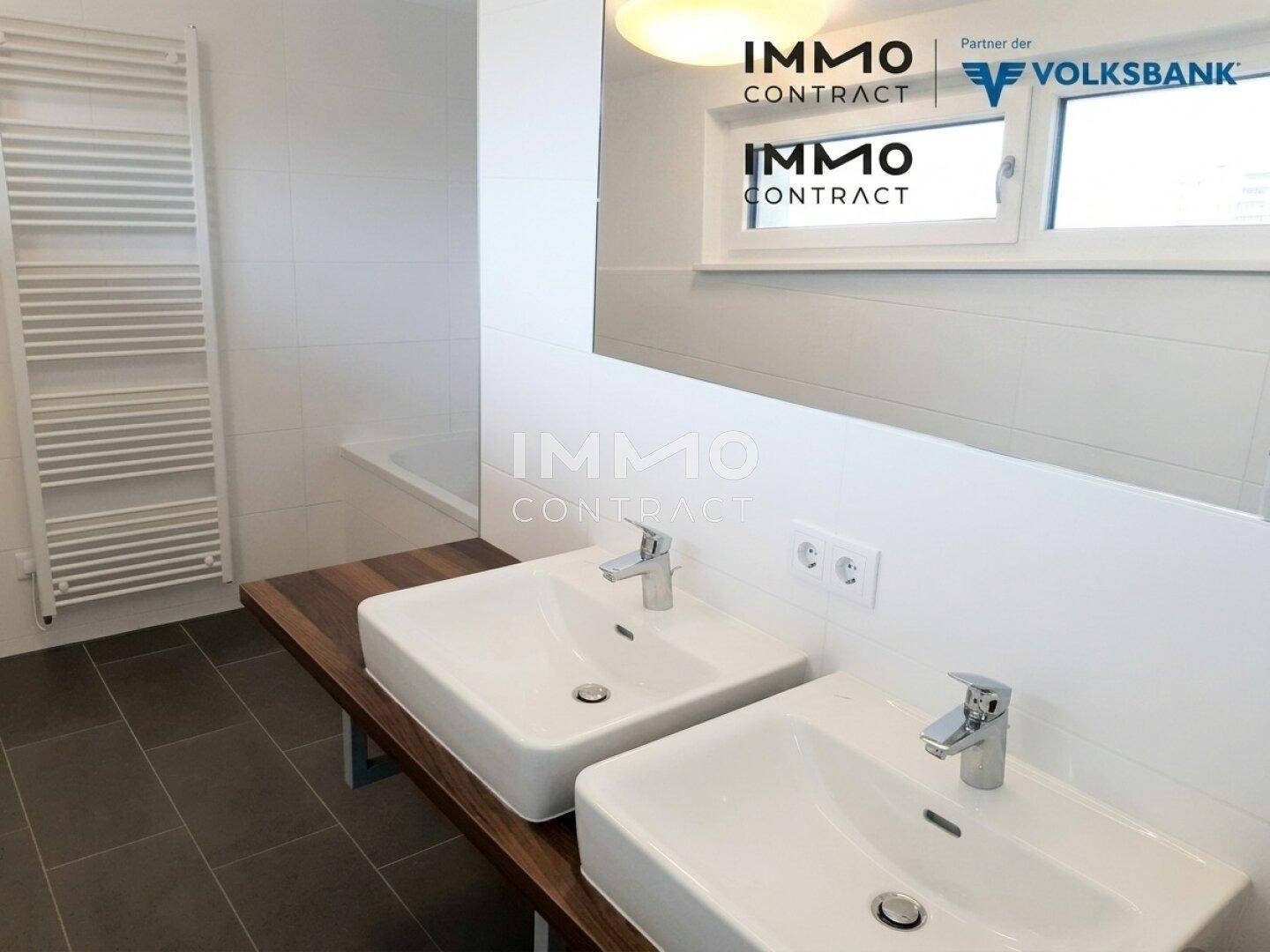 Modernes Badezimmer mit Doppelwaschbecken, Holzablage und Handtuchheizkörper, hell gefliest.
