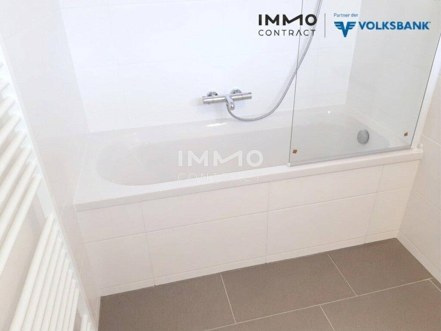 Helles Badezimmer mit Badewanne und Duschabtrennung, modern gefliest.