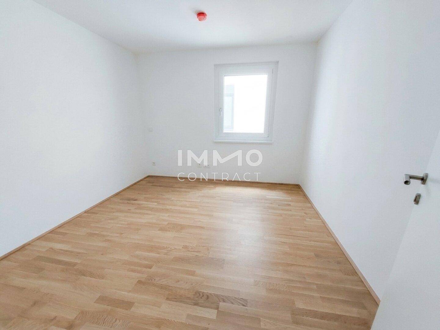 Helles Zimmer mit Parkettboden und einem Fenster, ideal als Schlaf- oder Arbeitszimmer.