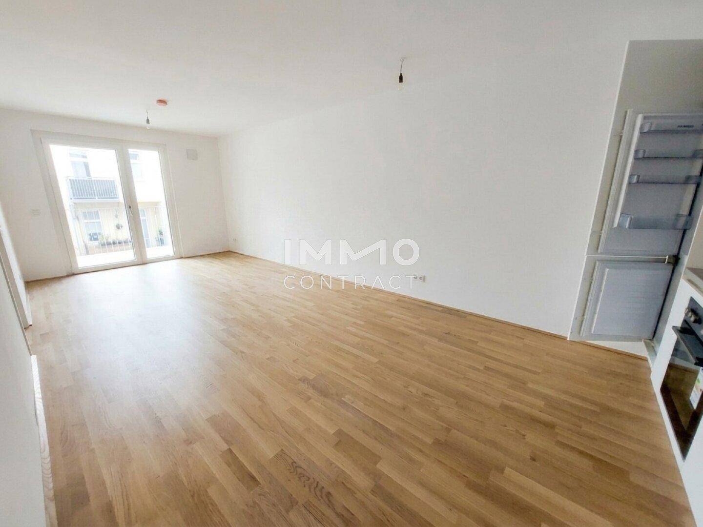 Heller Wohnbereich mit Holzboden und Zugang zu einem Balkon oder einer Terrasse.