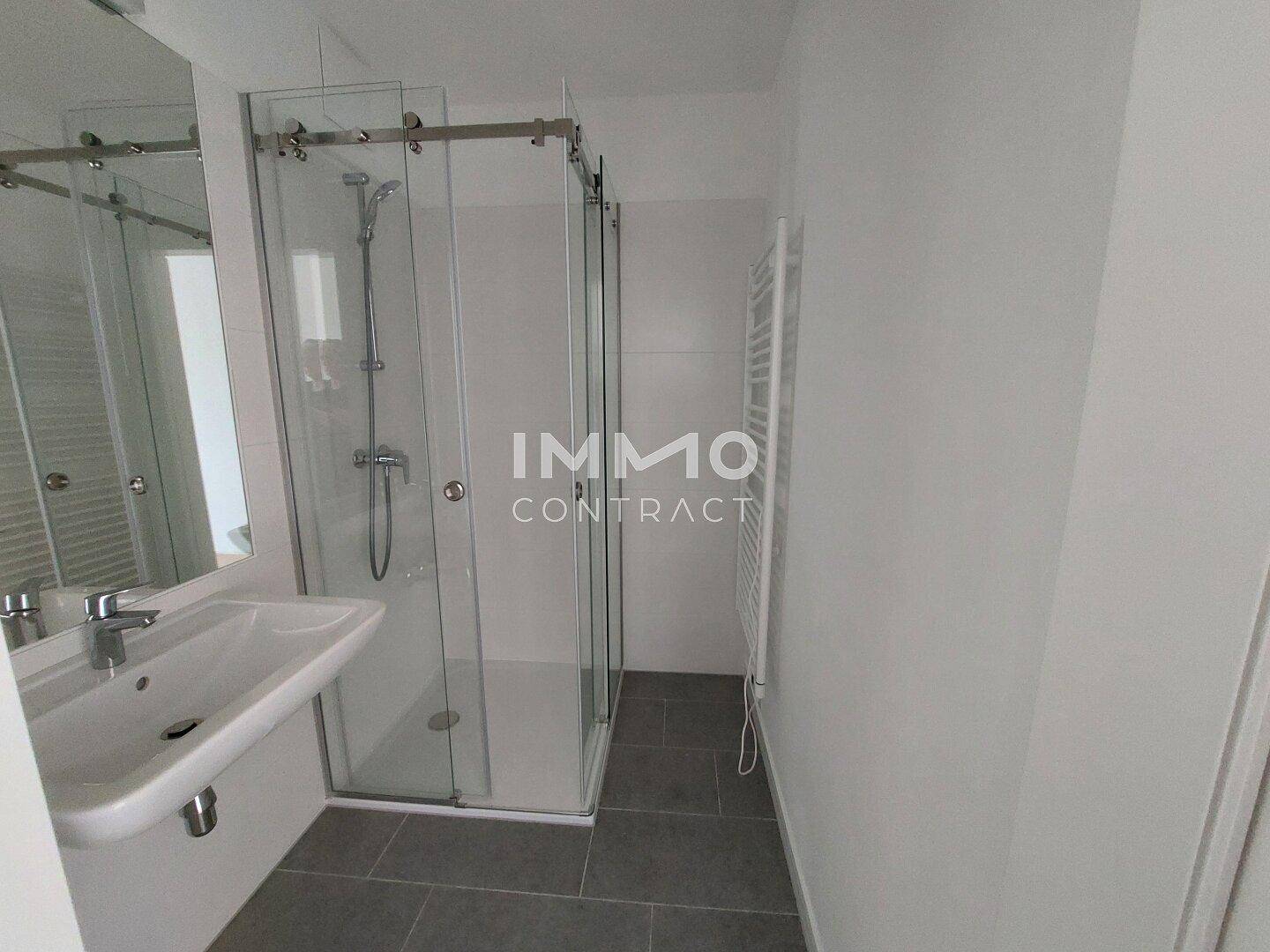Modernes Badezimmer mit Duschkabine, Waschbecken, Spiegel und Handtuchheizkörper an der Wand.