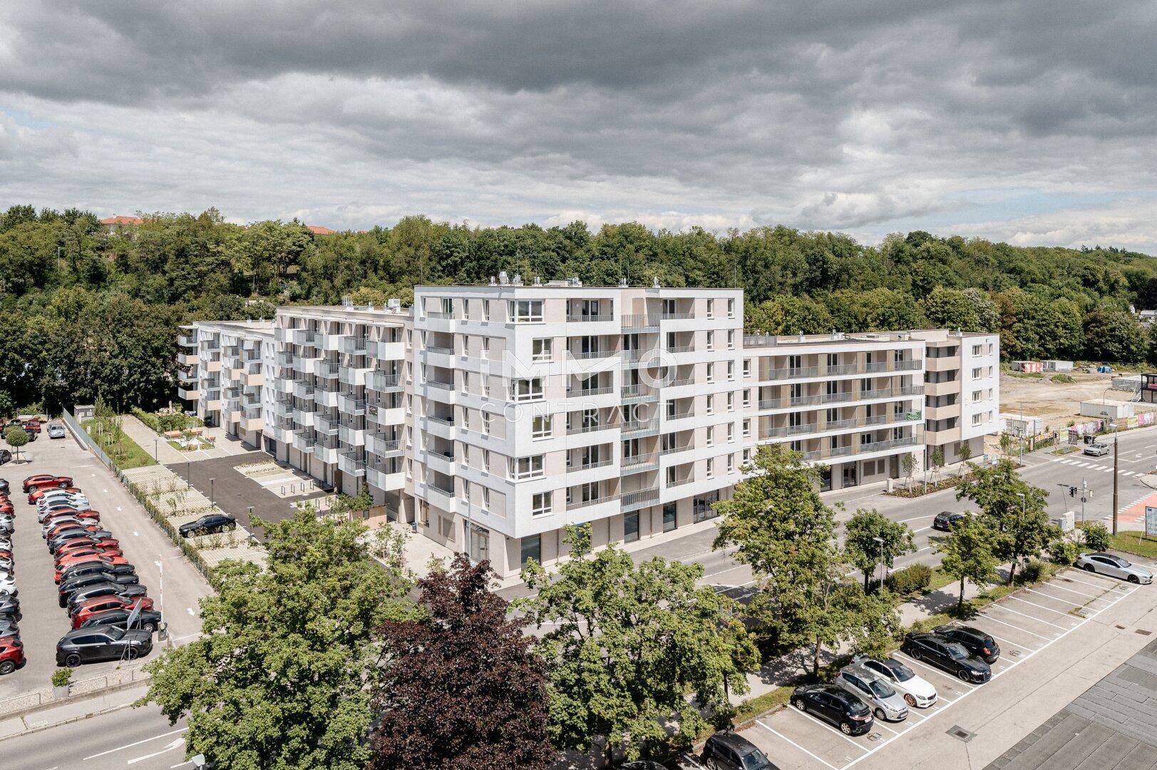 Luftaufnahme einer modernen Wohnanlage mit Parkplätzen und umliegenden Grünflächen.